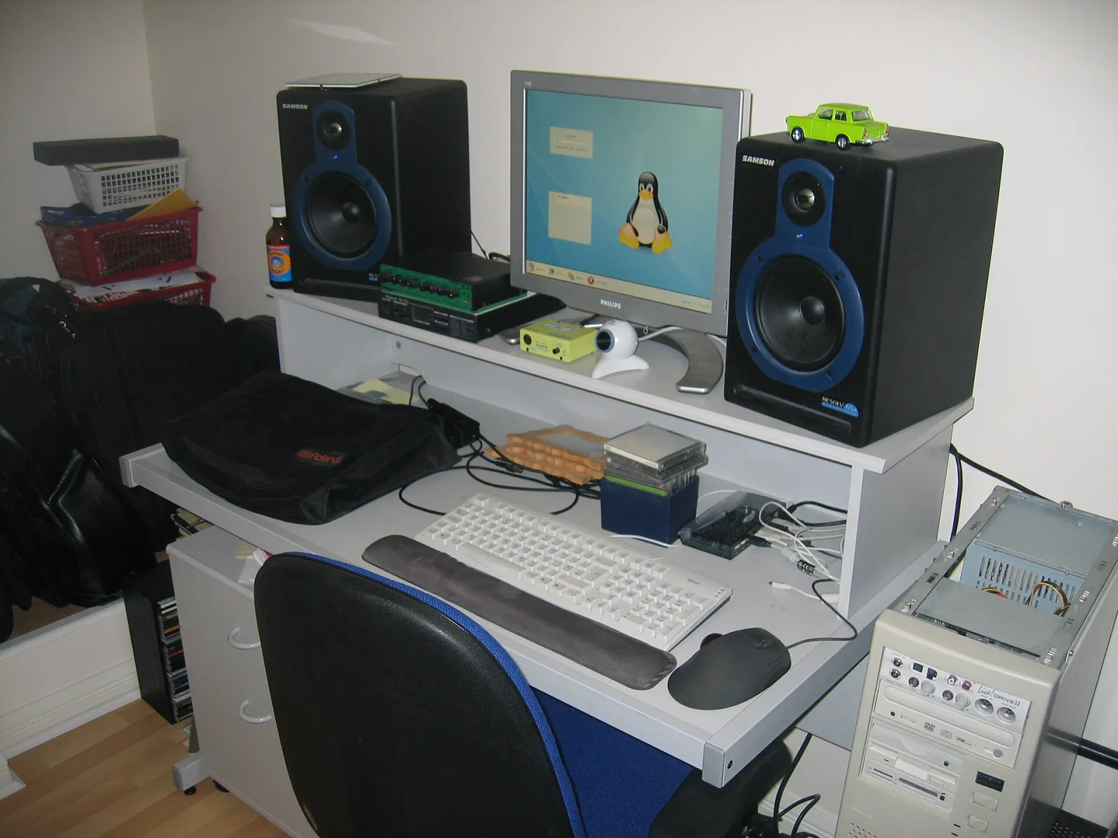 A home recording setup: a desktop computer with a monitor between two studio speakers, a keyboard and a mixer on a white desk.