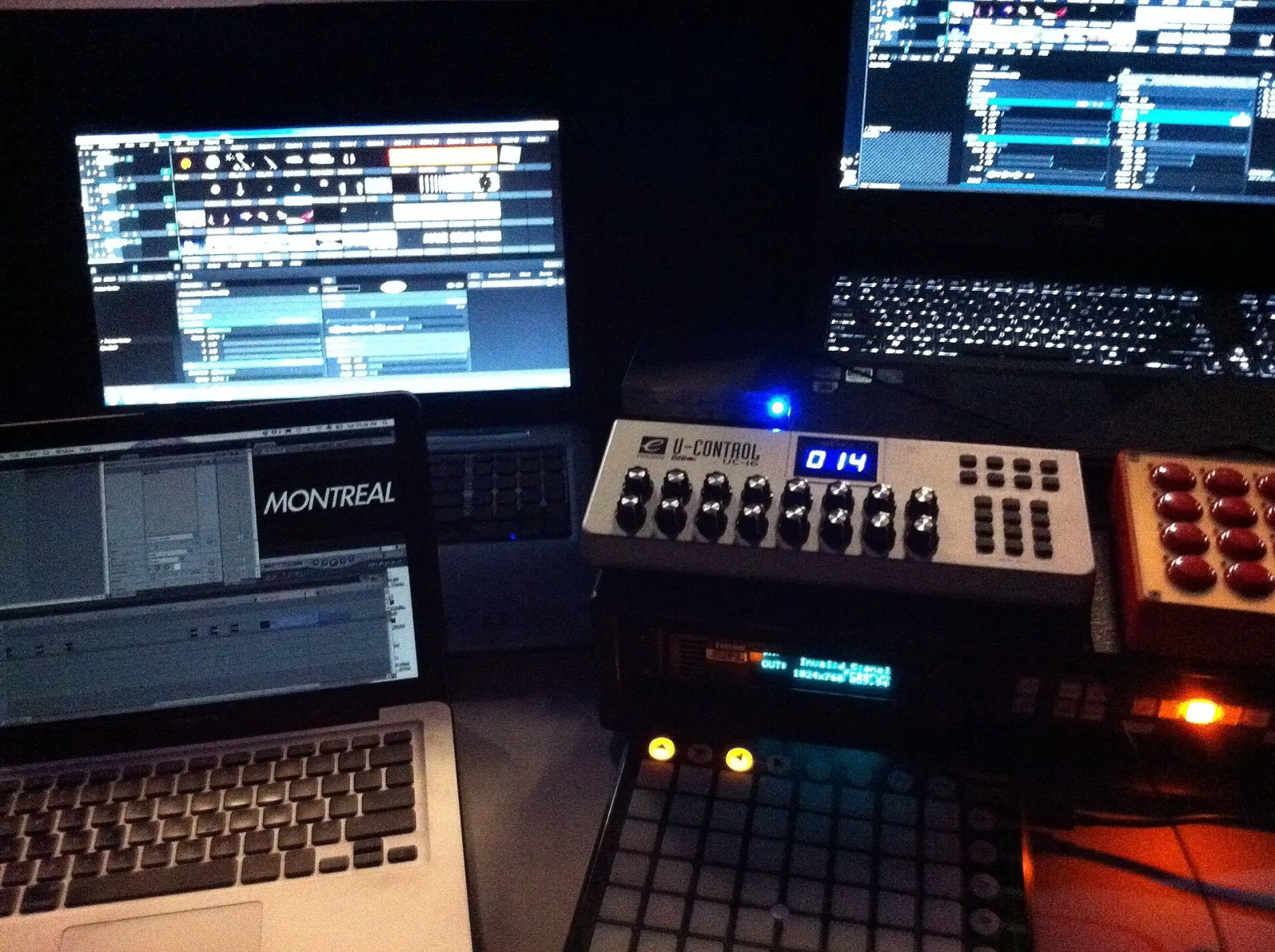 A touring VJ setup: two laptops running Resolume and a MacBook on a table, with a Novation Launchpad, a UC-16 fader controller and a Midi Fighter in front of them.